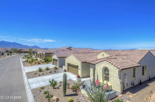 mediterranean / spanish home with a tile roof, driveway, an attached garage, a mountain view, and stucco siding