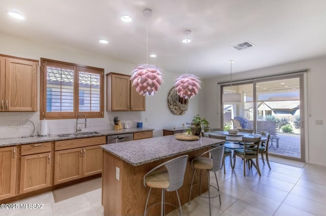 kitchen with a center island, light stone countertops, a sink, and visible vents