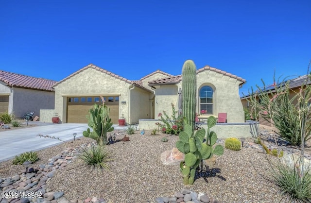 mediterranean / spanish home with stucco siding, concrete driveway, a tiled roof, and a garage