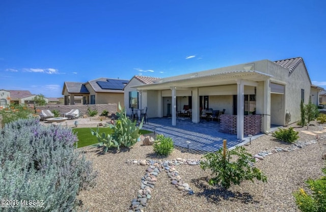 rear view of property featuring a tile roof, a patio, stucco siding, and fence