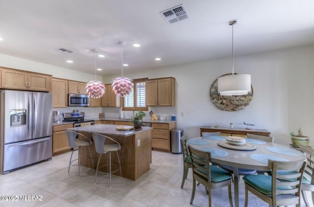 kitchen with a breakfast bar, visible vents, a center island, and stainless steel appliances