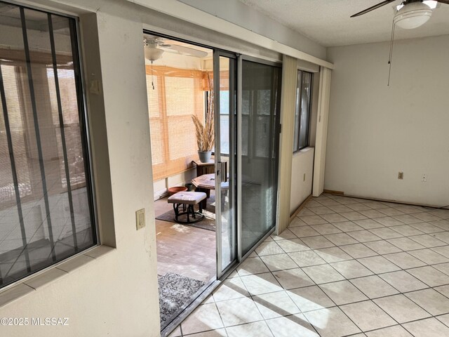 empty room with light tile patterned flooring, a wealth of natural light, and ceiling fan