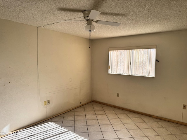 empty room featuring a textured ceiling, ceiling fan, and light tile patterned floors