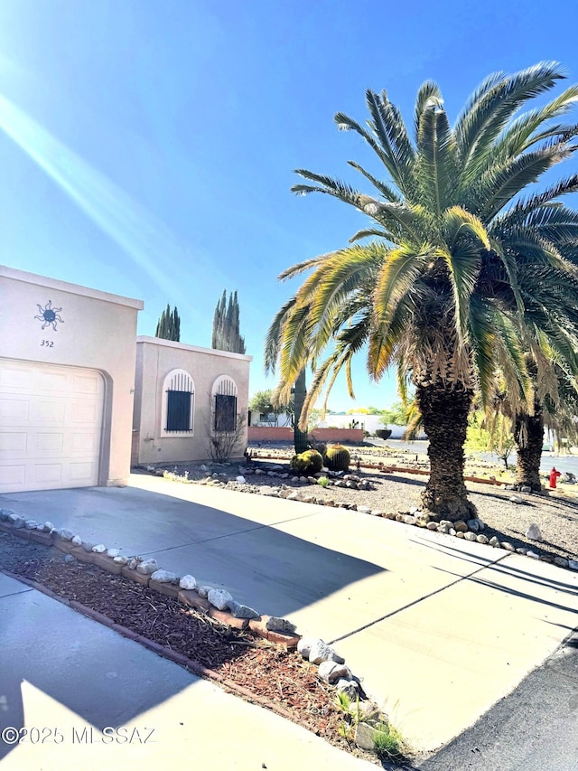 view of front facade with a garage, driveway, and stucco siding