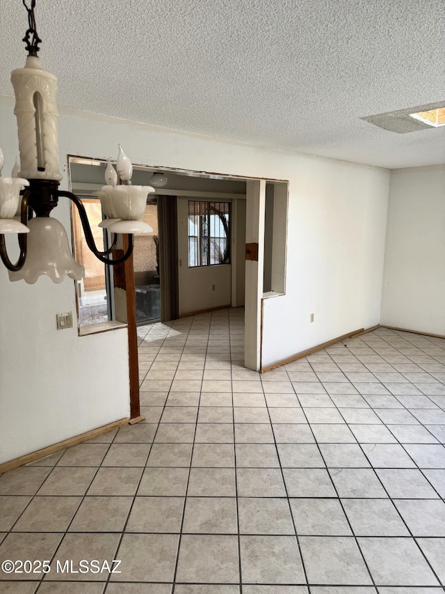 unfurnished room featuring baseboards, a textured ceiling, and light tile patterned floors