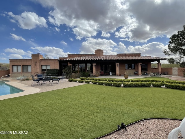 942 N Rancho Del Jefe Loop, Tucson, AZ 85748 - back of property featuring a patio area, a lawn, a chimney, an outdoor pool, and brick siding