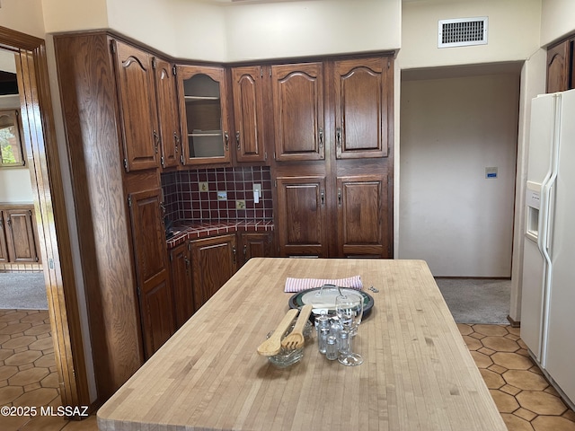 942 N Rancho Del Jefe Loop, Tucson, AZ 85748 - kitchen featuring butcher block counters, white fridge with ice dispenser, glass insert cabinets, tasteful backsplash, and light carpet