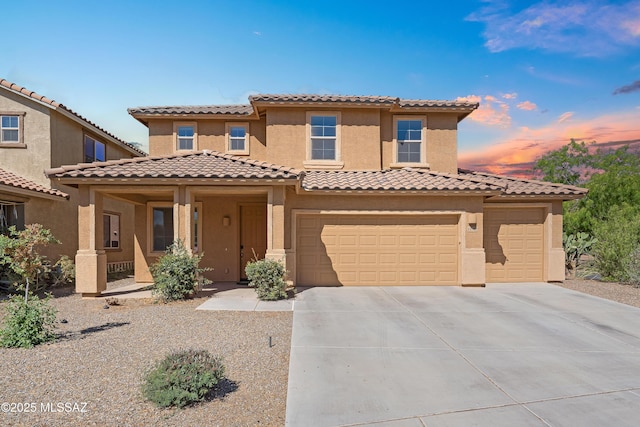 mediterranean / spanish house featuring driveway, a tiled roof, a porch, a garage, and stucco siding
