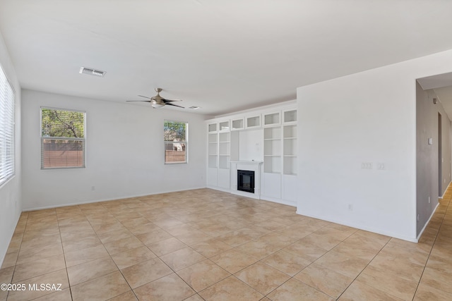 unfurnished living room with visible vents, a ceiling fan, a wealth of natural light, and light tile patterned floors