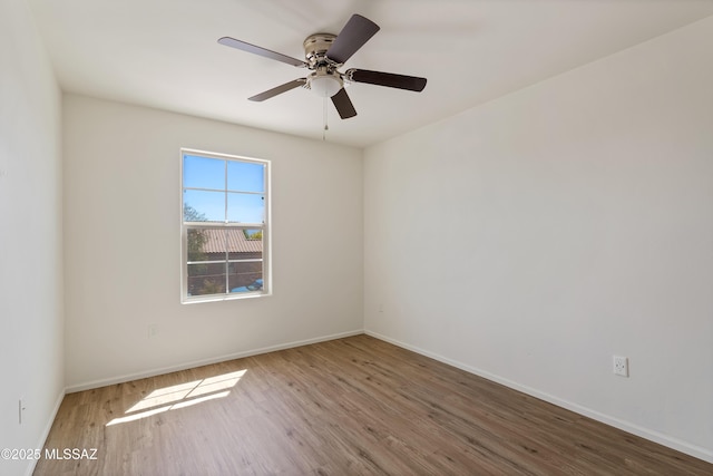 unfurnished room with wood finished floors, a ceiling fan, and baseboards