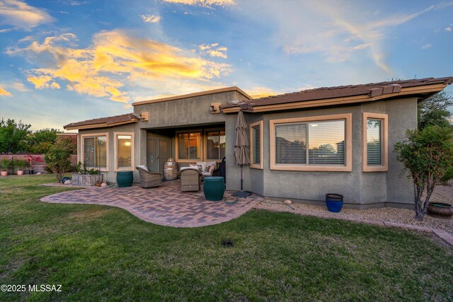 9224 S Big Tree Ln, Tucson, AZ 85756 - back of property at dusk with a yard, a patio, and stucco siding
