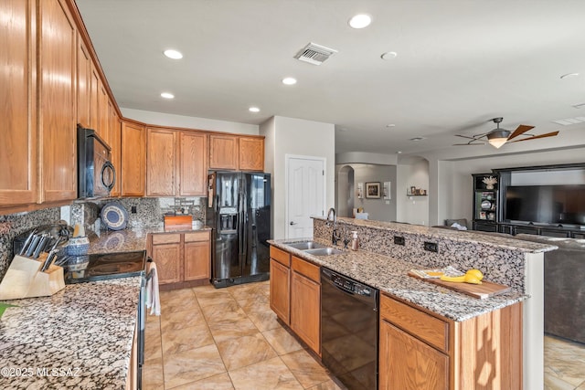 9224 S Big Tree Ln, Tucson, AZ 85756 - kitchen with a sink, black appliances, an island with sink, arched walkways, and visible vents