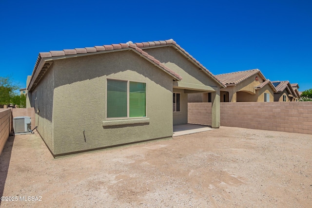 back of property with a patio, a tile roof, central air condition unit, stucco siding, and a fenced backyard
