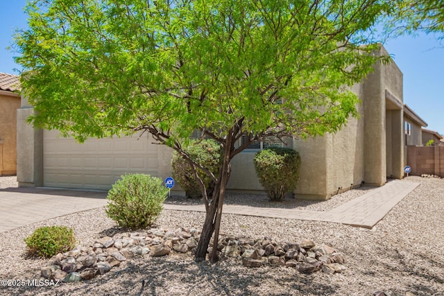view of property exterior with stucco siding, fence, a tile roof, and a garage