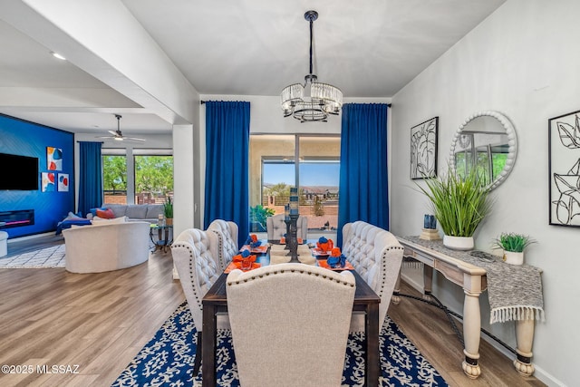 dining room with baseboards, wood finished floors, and ceiling fan with notable chandelier