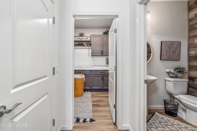 bathroom with baseboards, wood finished floors, and toilet