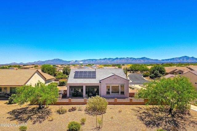 back of house with solar panels, a tiled roof, stucco siding, and a mountain view