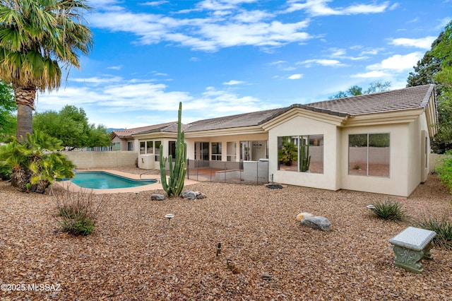 rear view of house with a fenced in pool, stucco siding, a fenced backyard, and a patio area