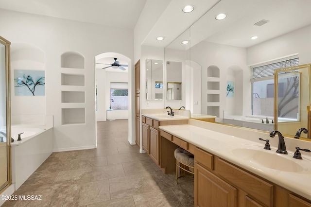 bathroom featuring built in shelves, a ceiling fan, a sink, and a garden tub