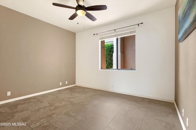 spare room featuring ceiling fan and baseboards
