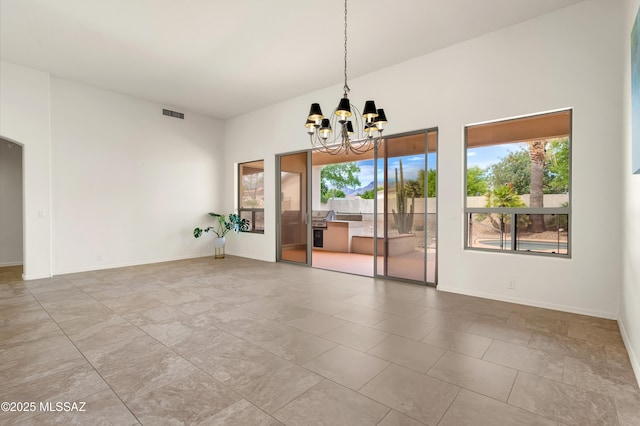 spare room featuring an inviting chandelier, baseboards, and visible vents