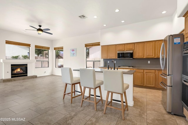 kitchen with appliances with stainless steel finishes, a breakfast bar, ceiling fan, visible vents, and recessed lighting