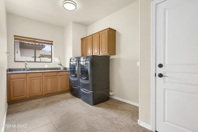 clothes washing area featuring baseboards, cabinet space, washer and clothes dryer, and a sink