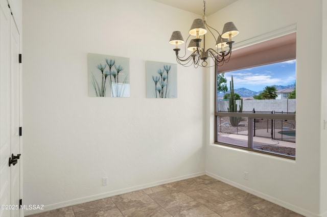unfurnished dining area with a mountain view, a chandelier, and baseboards