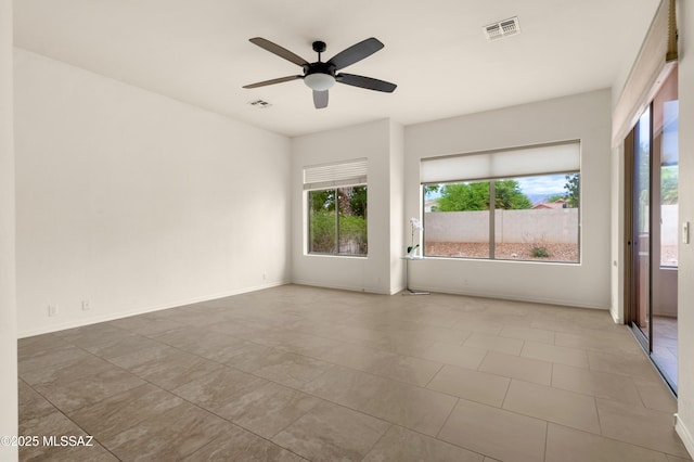 spare room featuring a ceiling fan, visible vents, and a wealth of natural light