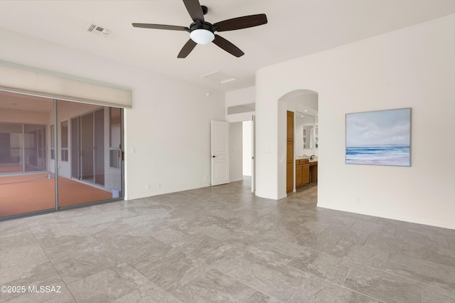 spare room with baseboards, visible vents, arched walkways, and a ceiling fan