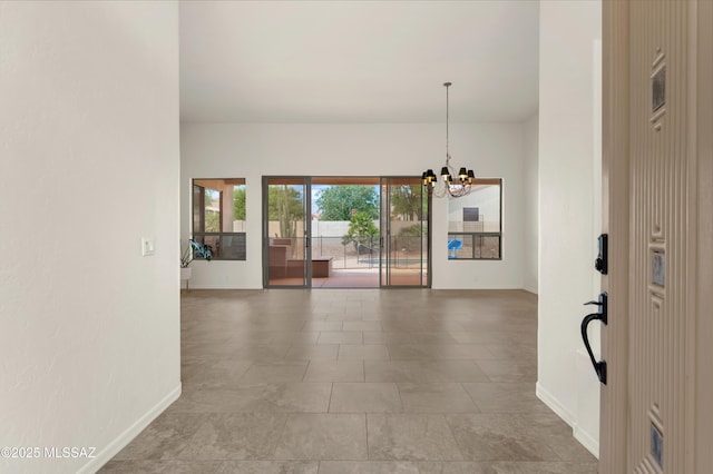 spare room featuring an inviting chandelier and baseboards
