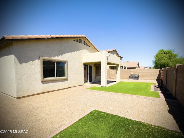 back of house with a lawn, a patio, a fenced backyard, and stucco siding