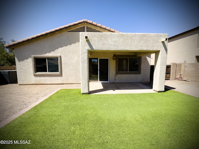 back of property with fence, a patio, stucco siding, and a yard