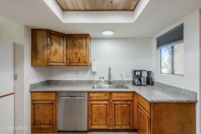 kitchen with a tray ceiling, dishwasher, brown cabinets, and a sink