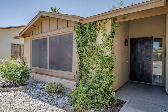 property entrance with stucco siding and board and batten siding