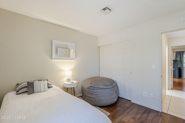 bedroom featuring a closet, visible vents, wood finished floors, and baseboards