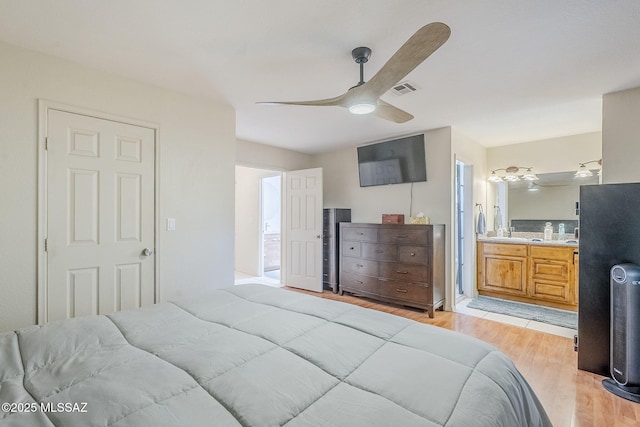 bedroom featuring connected bathroom, light wood-style floors, visible vents, and a ceiling fan