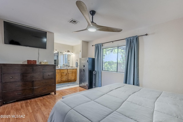 bedroom with a ceiling fan, ensuite bathroom, light wood-style flooring, and visible vents
