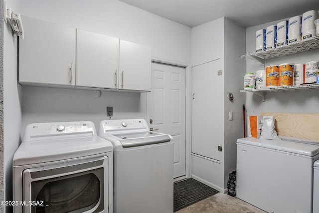 clothes washing area with washer and dryer and cabinet space