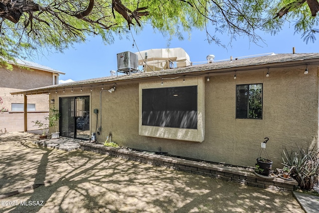 rear view of house with central AC unit, a patio area, and stucco siding