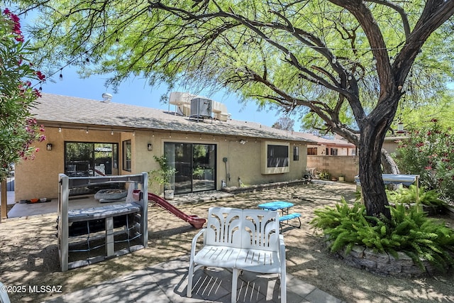 rear view of house featuring stucco siding, fence, and a patio
