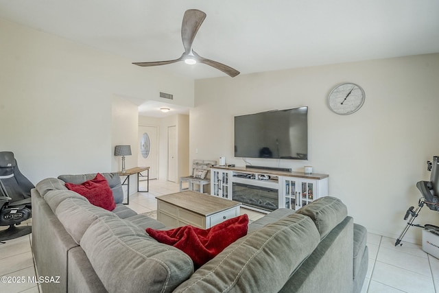 living room with a ceiling fan, visible vents, light tile patterned flooring, and a glass covered fireplace