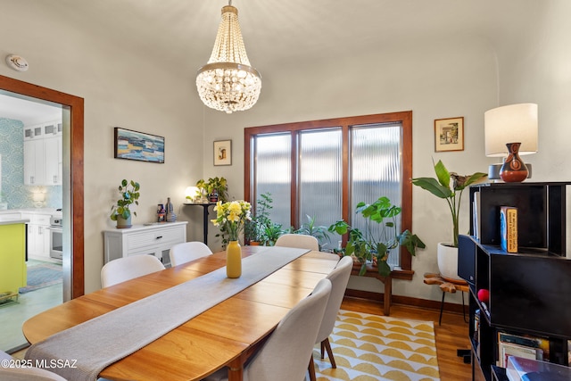 dining room with baseboards, a chandelier, and light wood finished floors