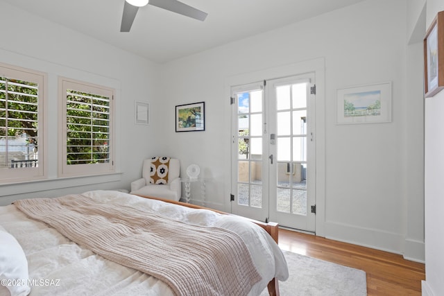 bedroom with ceiling fan, wood finished floors, multiple windows, and access to exterior