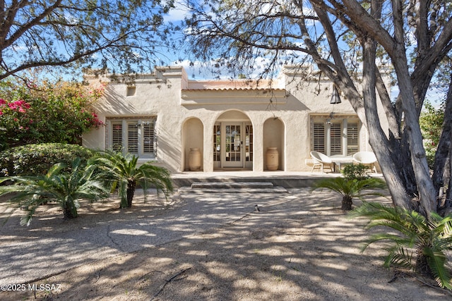 view of front of home featuring stucco siding, a patio area, and a tiled roof