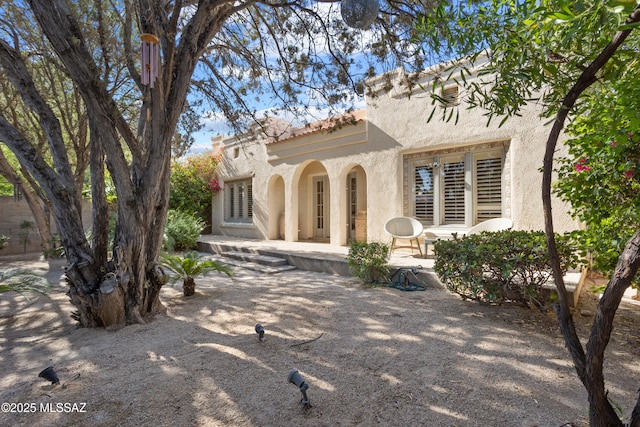 rear view of house featuring stucco siding and a patio area