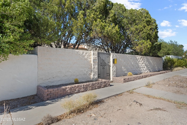 community / neighborhood sign featuring fence and a gate