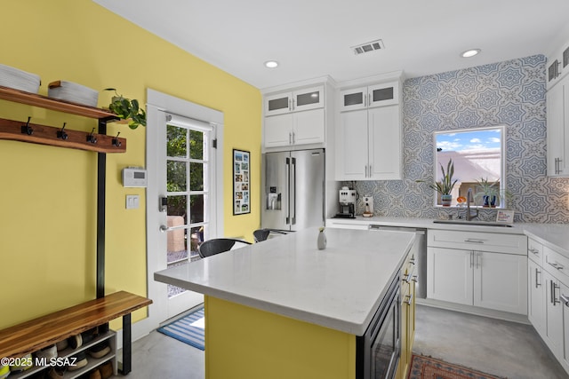 kitchen with white cabinets, a sink, a center island, stainless steel appliances, and visible vents