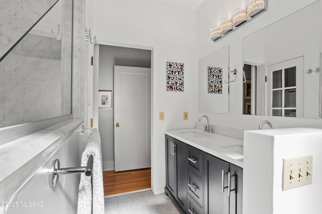 bathroom with double vanity, a tile shower, and a sink