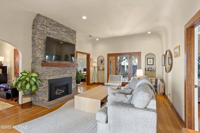 living room featuring visible vents, arched walkways, a fireplace, wood finished floors, and recessed lighting